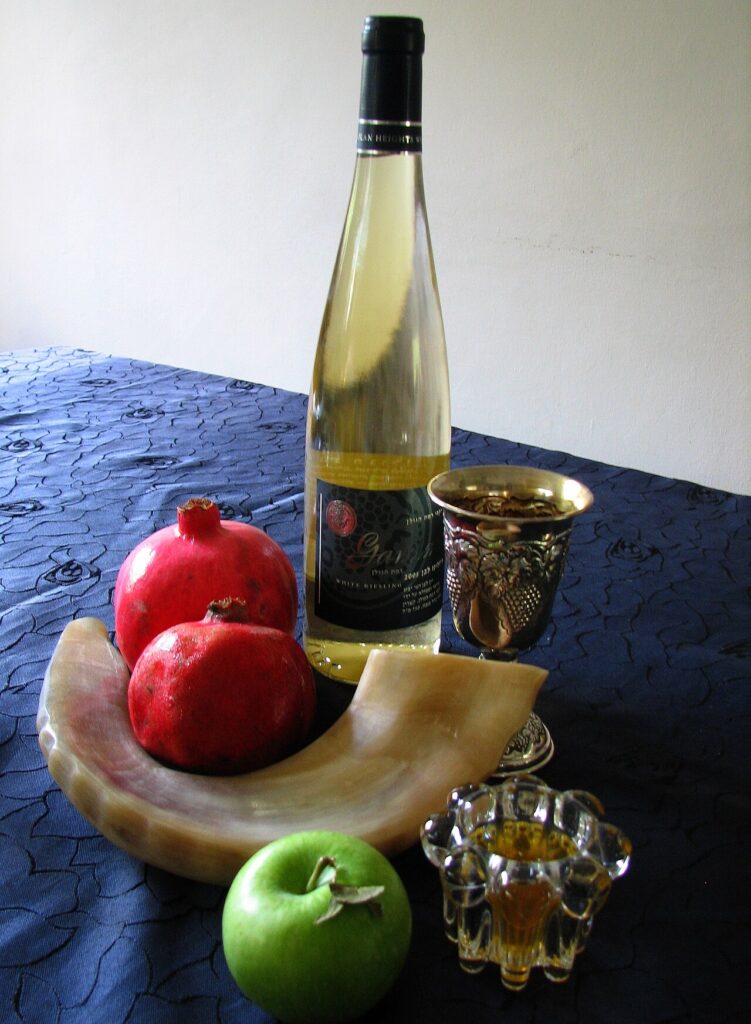 Rosh Hashanah kosher foods on the holiday table: pomegranate, apple, honey, wine, and a shofar